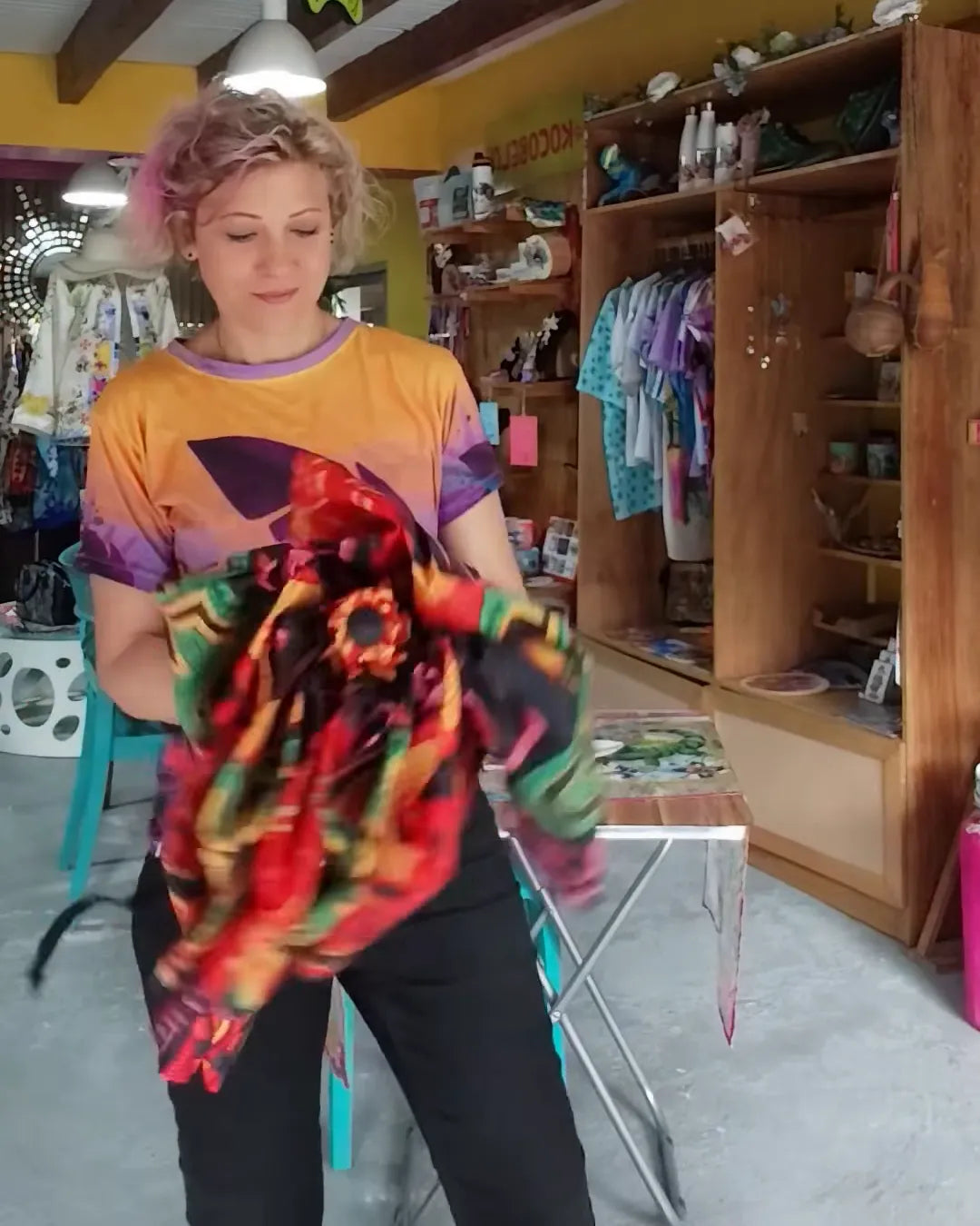 Serena dentro de la tienda de Boquete, con ropa estampada en los percheros